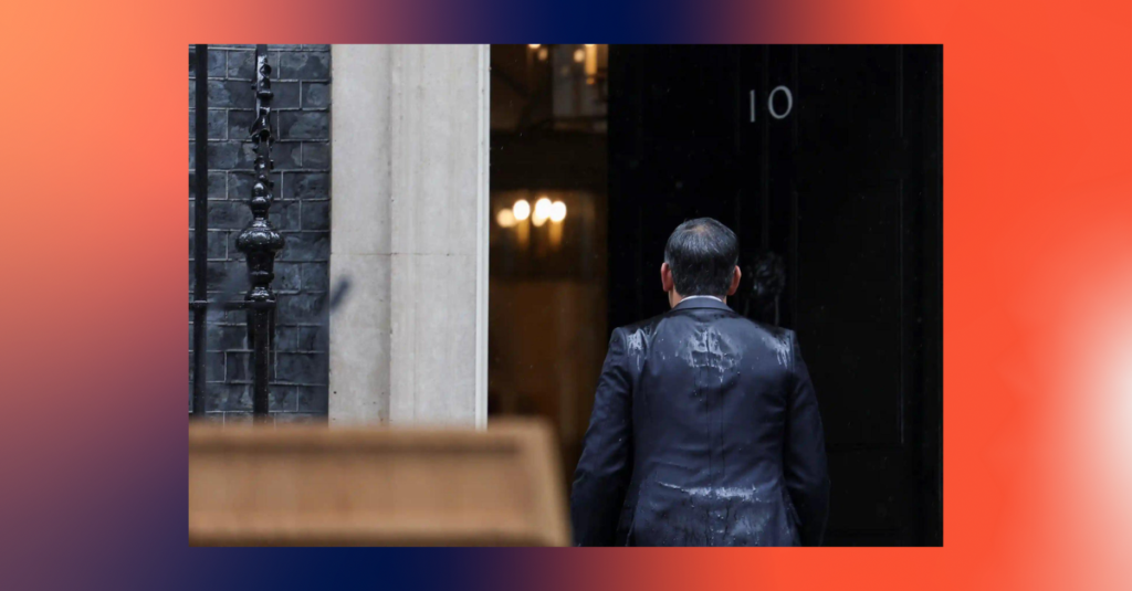 A photo of a rain-drenched Rishi Sunak walking into 10 Downing Street.